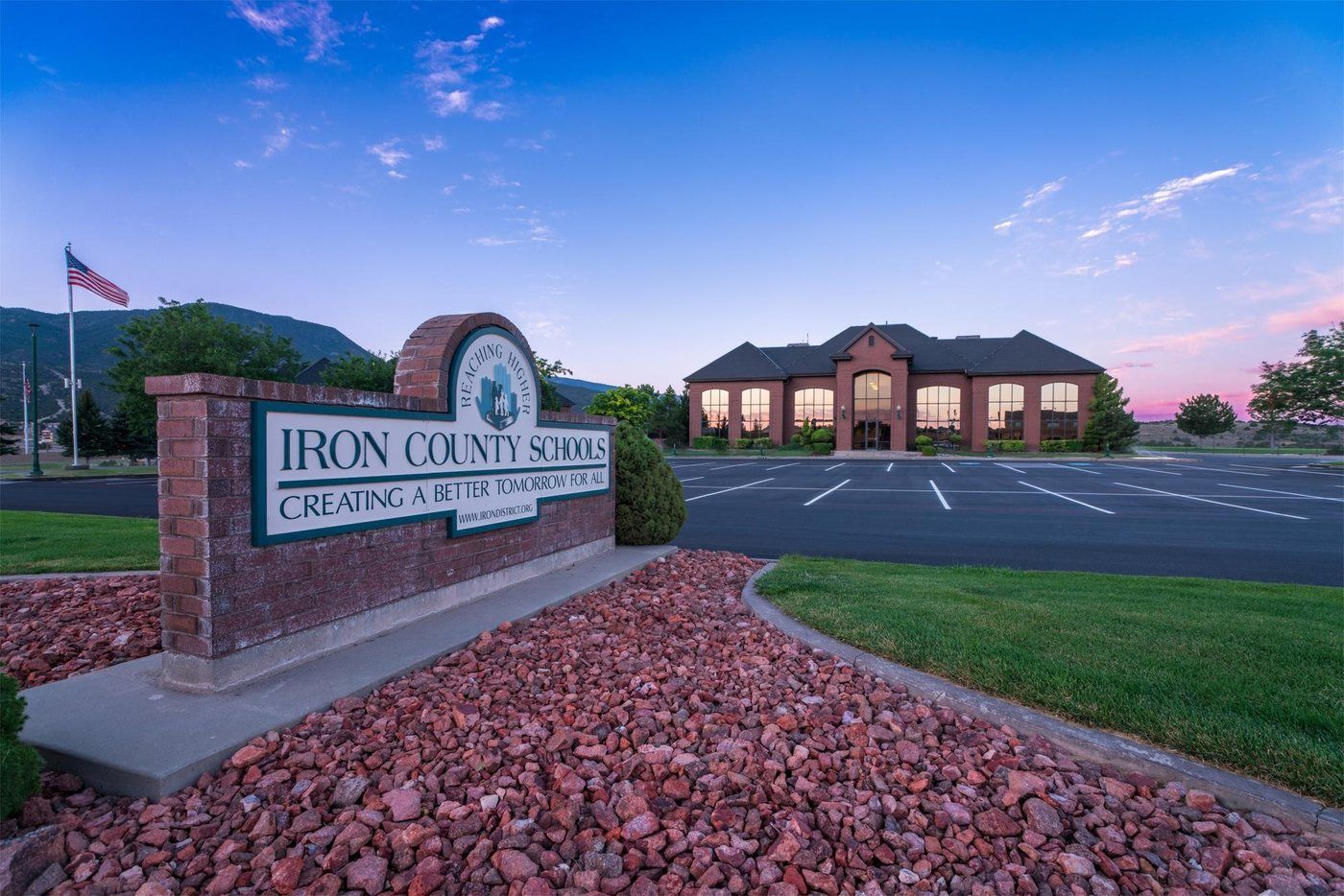 The Iron County School District office in Cedar City at dusk, with the district sign and flag.