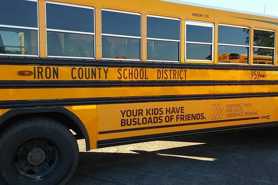 An Iron County School District bus parked in a lot on a sunny morning.